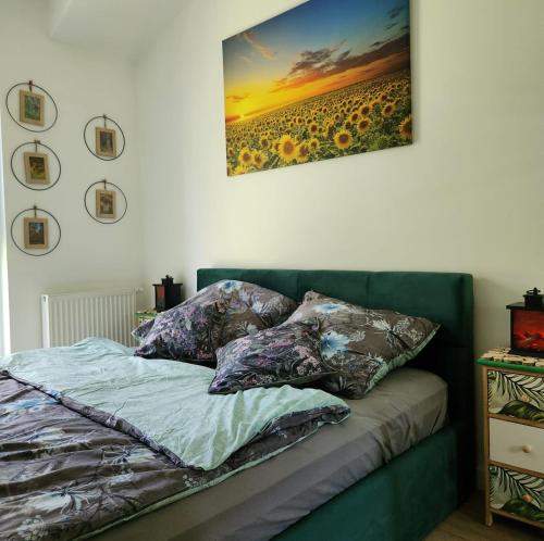 a bed with pillows and a painting on the wall at Green Apartament Chill Modlin Airport in Kazuń Nowy