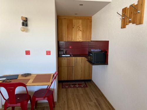a small kitchen with a table and red chairs at Chez Chantal in Siviez