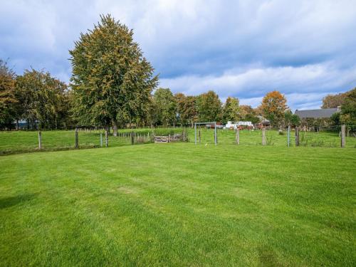 a large grass field with a fence and trees at Spa Cottage in Fagnes in Waimes