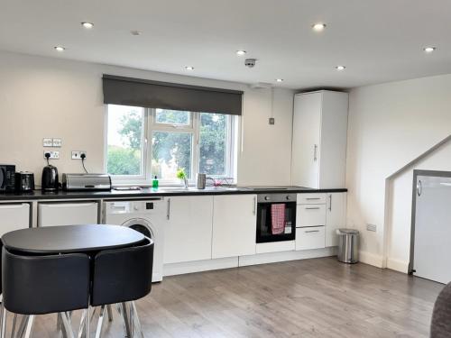 a kitchen with white cabinets and a table and chairs at Hatton apartments HEATHROW AIRPORT- FREE parking-Free underground to and from Heathrow Airport Hatton Cross SEE picture-SEE LONDON fast Hatton cross to central London 30min in London
