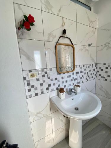 a white bathroom with a sink and a mirror at Thanas Apartment in Himare
