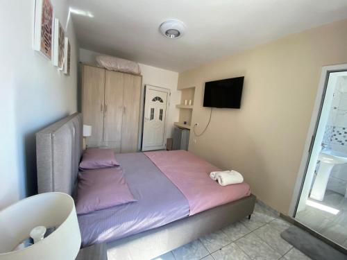 Cette chambre comprend un lit avec des draps violets et une télévision. dans l'établissement Thanas Apartment, à Himarë