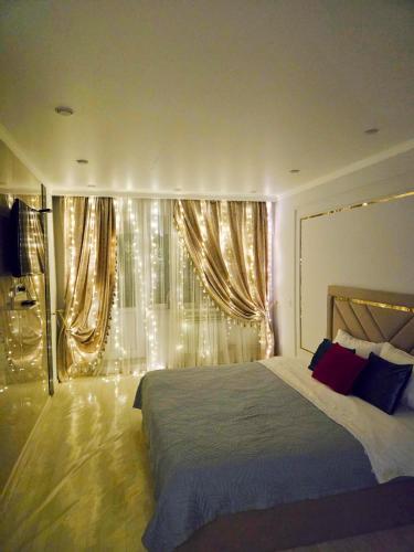 a bedroom with a large bed and a window with lights at Уютная квартира в хорошей точке города in Taraz