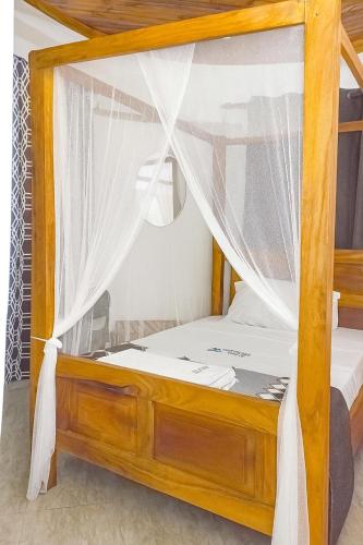 a bedroom with a canopy bed with curtains at Escape Hole in Diani Beach