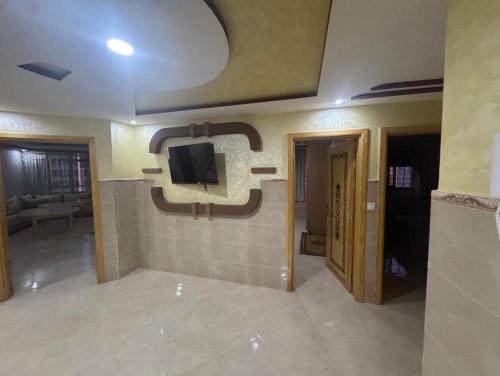 un salon avec une télévision sur un mur dans l'établissement Wassime location, à Taourirt