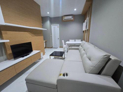 a living room with a white couch and a tv at The sea forest 101 in Rayong