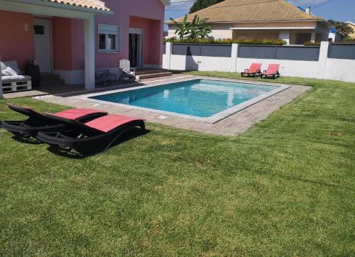 a swimming pool with two lounge chairs in a yard at Family Villa Pool & Beach in Caparica