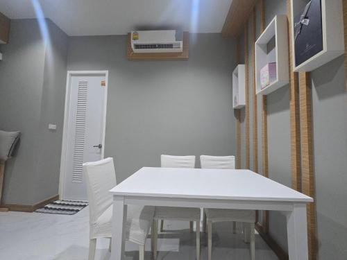 a dining room with a white table and white chairs at The sea forest 101 in Rayong