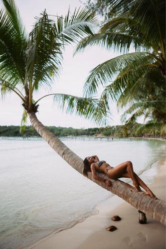 a woman laying on a palm tree on a beach at Kood Life in Ko Kood