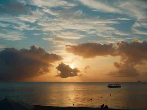 a sunset on the beach with a boat in the water at Date Villa Awaji in Sumoto