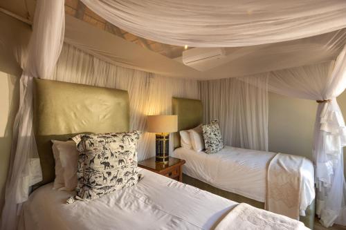 a bedroom with two beds and a canopy at Karongwe - River Safari Lodge in Hoedspruit