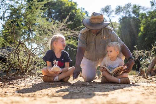 a man and two little girls sitting on the ground at Karongwe - River Safari Lodge in Hoedspruit