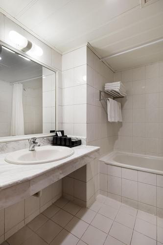 a bathroom with a sink and a tub and a mirror at Moonlight Hotel in Hsinchu City