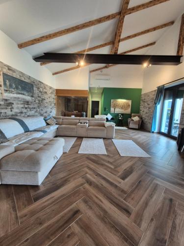 a large living room with wooden floors and a brick wall at Four Seasons Luxory Vendégház in Nyíregyháza