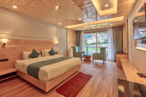 a bedroom with a large bed and a table and chairs at Shivalaya Retreat - A River Side Resort in Manāli