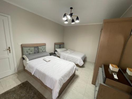 a bedroom with two beds and a dresser in it at Modern Comforts Await! Spacious 2BR 2Bath w Free WiFi Stylish Furniture in Madinaty