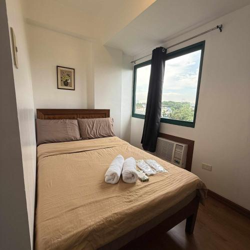 a bedroom with a bed with two white towels on it at Isabelle Garden Hotel & Suites in Manila