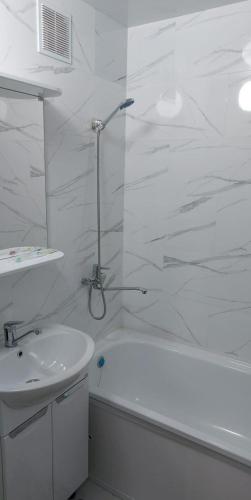 Un baño blanco con ducha y lavabo. en Квартира, en Pavlodar