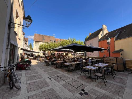 an outdoor restaurant with tables and chairs and umbrellas at Escale secrète Montargis Jacuzzi Terrasse Parking gratuit in Montargis