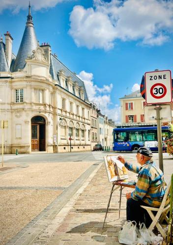a man sitting in a chair next to a sign at Escale Secrète Détente Montargis Parking Gratuit in Montargis