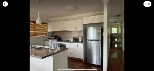 DeagonにあるRoom in a Beautiful Queenslander Houseの白いキャビネットとステンレス製の冷蔵庫を備えたキッチン