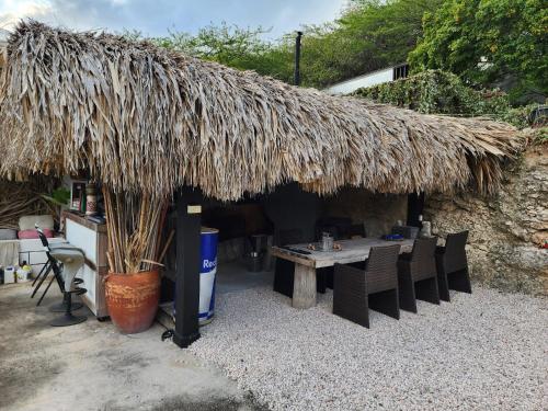 a patio with a table and a straw roof at Nice Life appartments in Willemstad