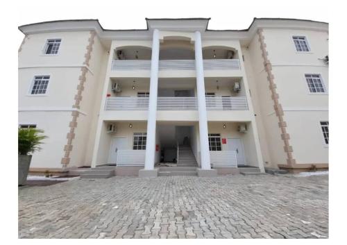 a large white building with columns and a courtyard at Fort Fountain Apartments in Abuja