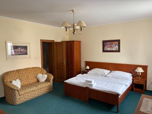 a bedroom with a bed and a couch and a chair at Penzion 77 - Garni in Pezinok