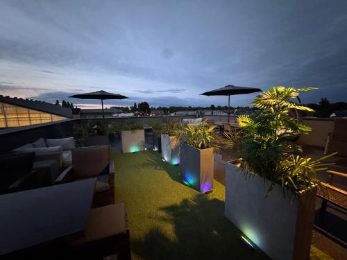 ミュンスターにあるMARRAM Suitehotelの夜の植物とパラソルのある屋上パティオ