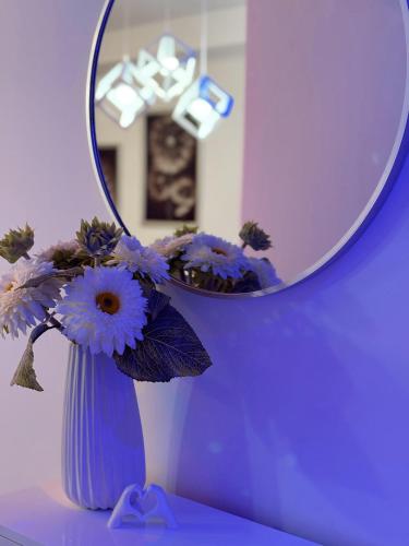 a blue vase with purple flowers in front of a mirror at Honey apartments in Ledine
