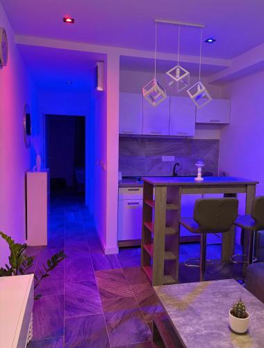 a kitchen with purple lighting and a kitchen island at Honey apartments in Ledine