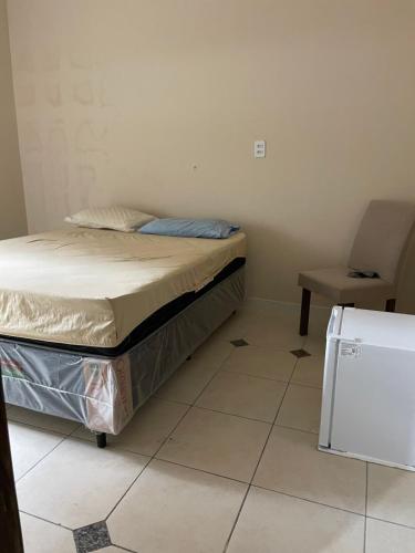 una piccola camera da letto con un letto e una sedia di Quartos Privativos Stella Maris a Salvador