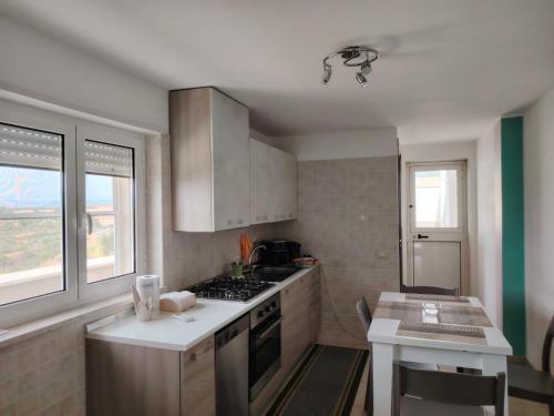 a kitchen with white cabinets and a stove top oven at La Casetta di Bea in Bernalda