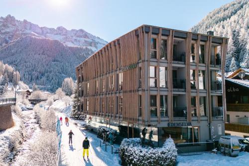 Ein Gebäude mit Leuten, die draußen im Schnee stehen. in der Unterkunft Mountain Design Hotel EdenSelva in Wolkenstein in Gröden