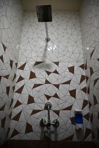 a bathroom with a white and brown tiled wall at Hotel Om Elite Stay in Jaipur