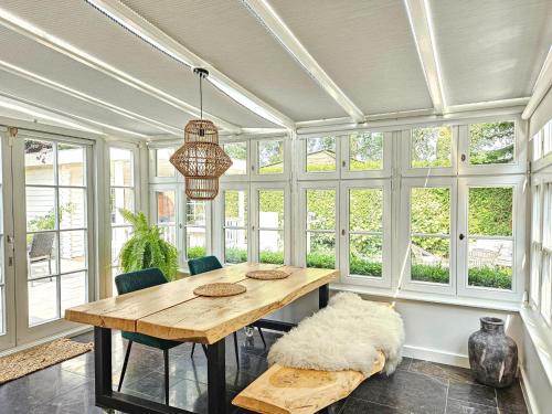 a dining room with a table and chairs and windows at Chalet Kieftveen with hot tub for four Person in Voorthuizen