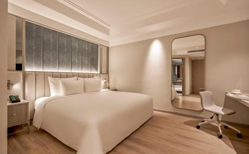 a bedroom with a large white bed and a mirror at La Siesta Premium Lakeside in Hanoi