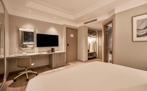 a bedroom with a bed and a desk and a television at La Siesta Premium Lakeside in Hanoi