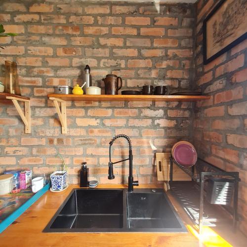 a kitchen with a sink and a brick wall at Your home in the Cape in Cape Town