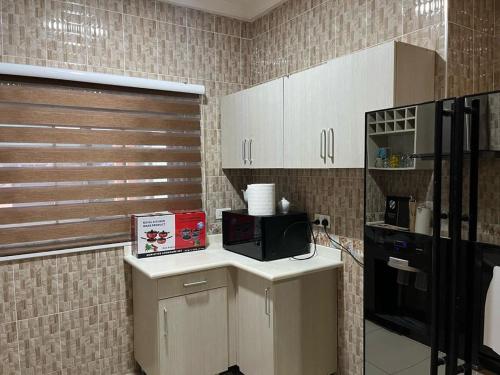 a kitchen with white cabinets and a black microwave at Self compound beautiful three bedroom house in Accra