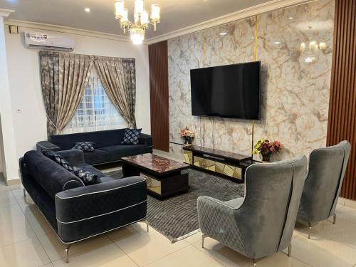 a living room with a couch and a tv on a wall at Self compound beautiful three bedroom house in Accra