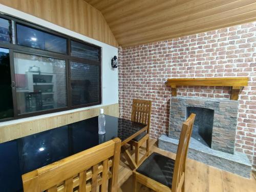 a dining room with a brick fireplace and a table and chairs at Drishya Stay With a View in Mangpu