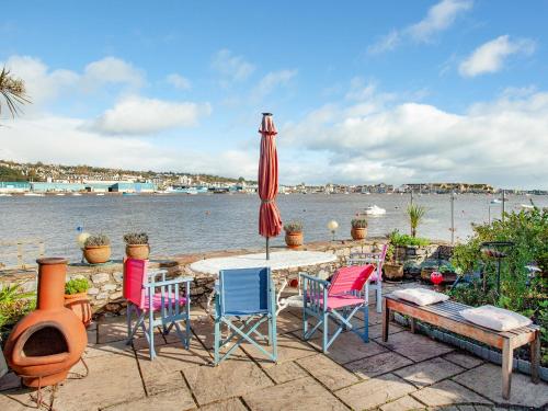 einen Tisch mit Stühlen und einen Regenschirm neben dem Wasser in der Unterkunft Port View Cottage in Shaldon