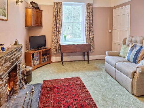 a living room with a couch and a tv at Carreg Yr Eos - Cottage in Fishguard