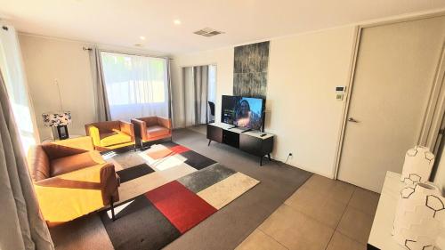 a living room with a couch and chairs and a television at Timeless Tranquility in Belconnen