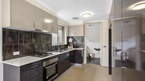 a kitchen with white cabinets and a stove top oven at Timeless Tranquility in Belconnen