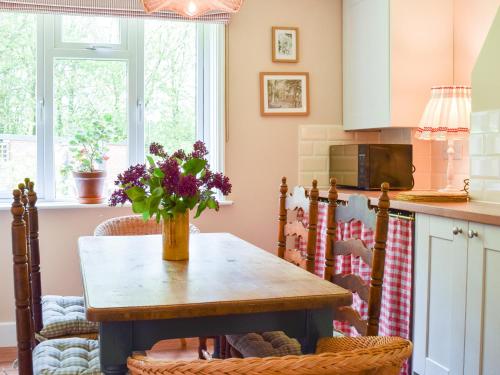 une cuisine avec une table avec un vase de fleurs dessus dans l'établissement Club Cottage, à Dummer