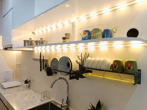 - une cuisine avec un évier et une étagère avec de la vaisselle dans l'établissement Căn studio tại Sentosa Hải Phòng view sông phố cao tầng, à An Khê