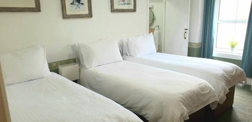 two beds with white sheets in a hotel room at The Osprey in Kingussie