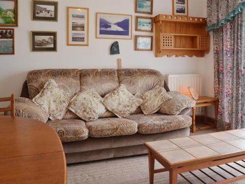 a living room with a brown couch and a table at Glan-Mor in Pwllheli